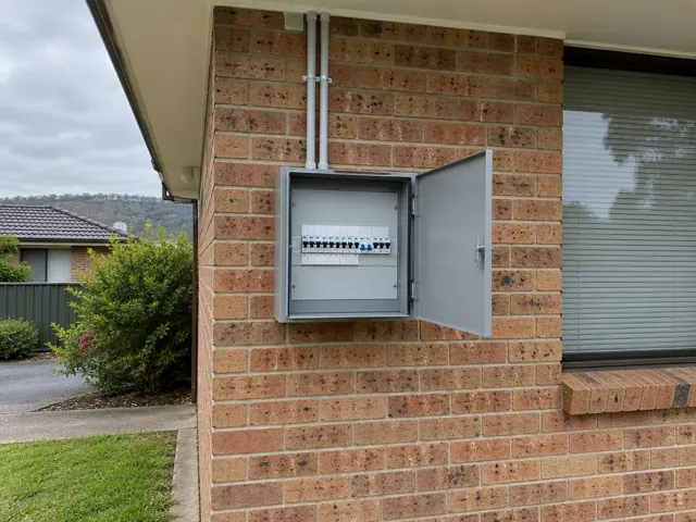 Exterior switchboard mounted on a brick wall beside a window in Warners Bay